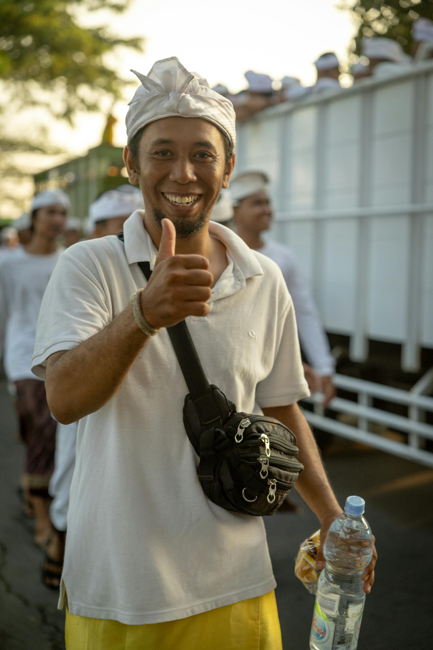Happy man giving thumbs up gesture during outdoor festival, embracing joyful culture.